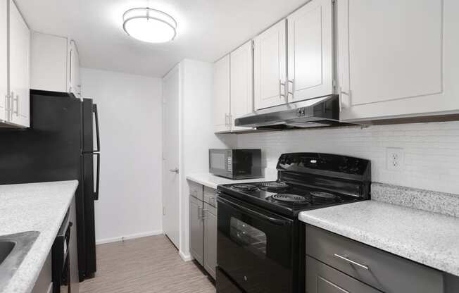 a kitchen with white cabinets and black appliances and a black refrigerator