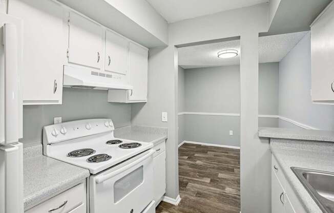 A white kitchen with a stove top oven and a sink.