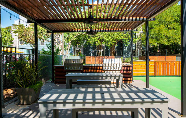 a picnic table and benches under a pergola on a patio