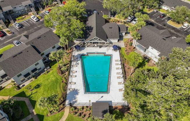 a birds eye view of a swimming pool in a neighborhood with houses and trees