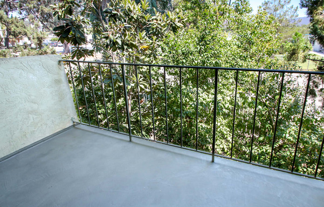 a balcony with a black railing and trees on it