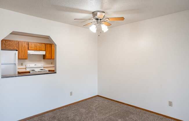 an empty room with a ceiling fan and a kitchen. Fargo, ND Westview Towers Apartments