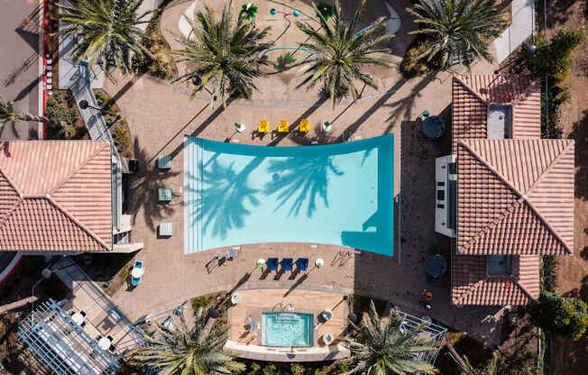 A swimming pool surrounded by palm trees and a few people.