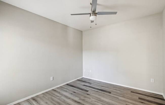 A room with a ceiling fan and wooden flooring.