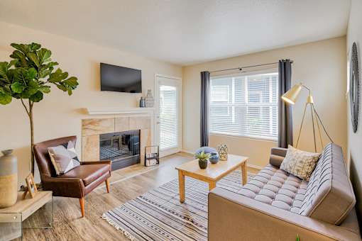 A living room with a fireplace, a couch, a chair, a coffee table, and a plant.