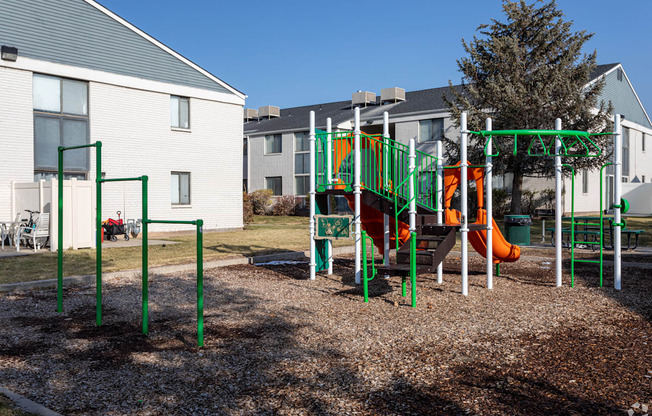 A playground with a green slide and orange slide.