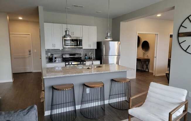 A modern kitchen with a bar stool and a white chair.