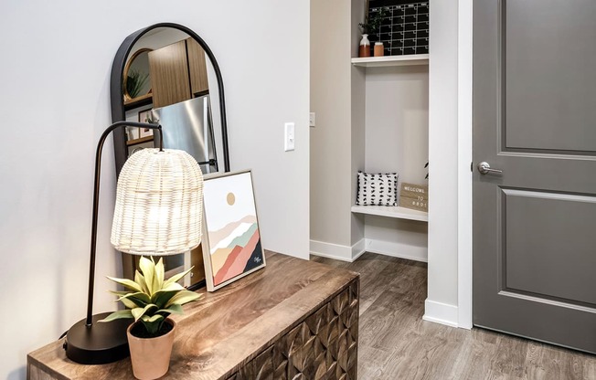 a living room with a mirror and a table with a plant and a dresser