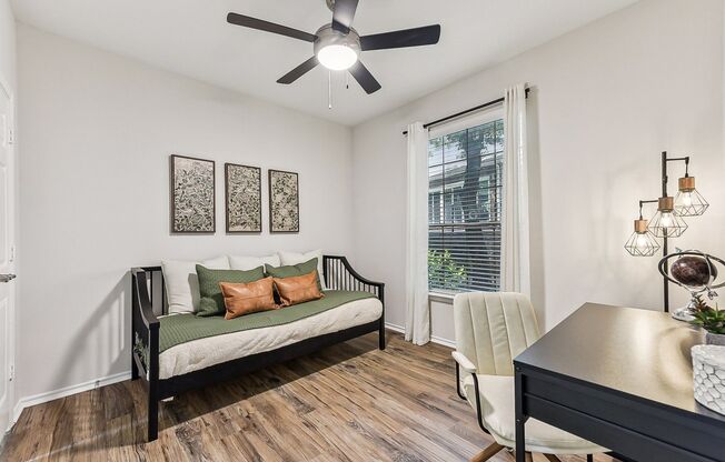 A room with a ceiling fan, a sofa, a chair, and a table.