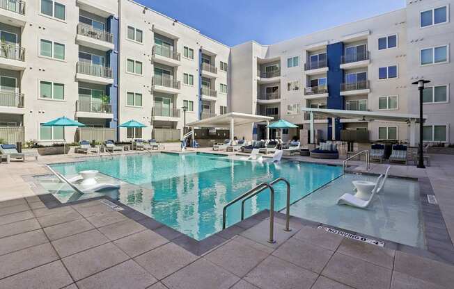A large swimming pool in front of apartment buildings.