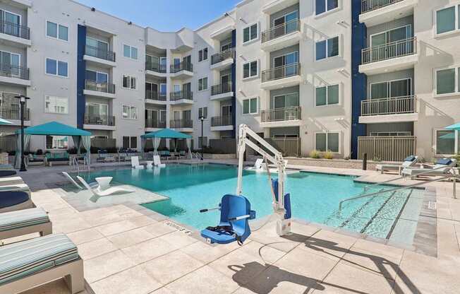 A swimming pool with a diving board in front of apartment buildings.