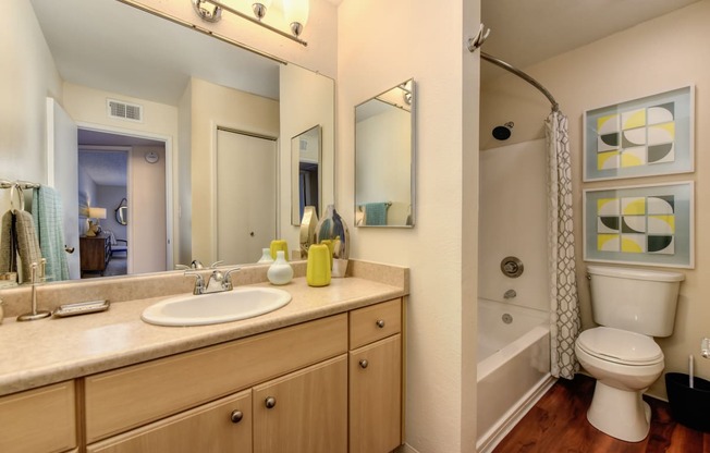 Model bathroom with long sink vanity counters, one sink, tub/shower enclosure and toilet