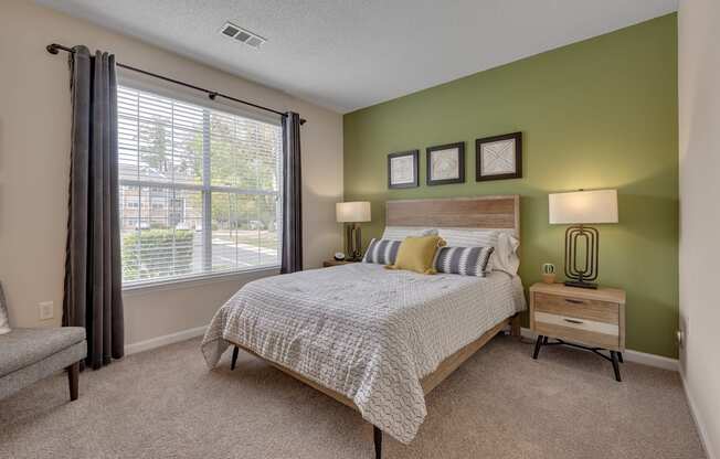 A bedroom with a bed, nightstand, and window.