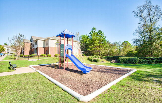 A playground with a blue slide and a red and blue structure.