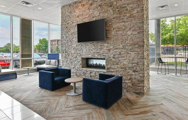 a lobby with two blue chairs and a stone fireplace