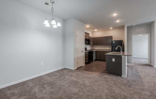 an empty living room with a kitchen in the corner
