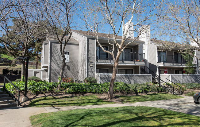A grey building with a tree in front of it at Kirker Creek Apartments, Pittsburg, CA