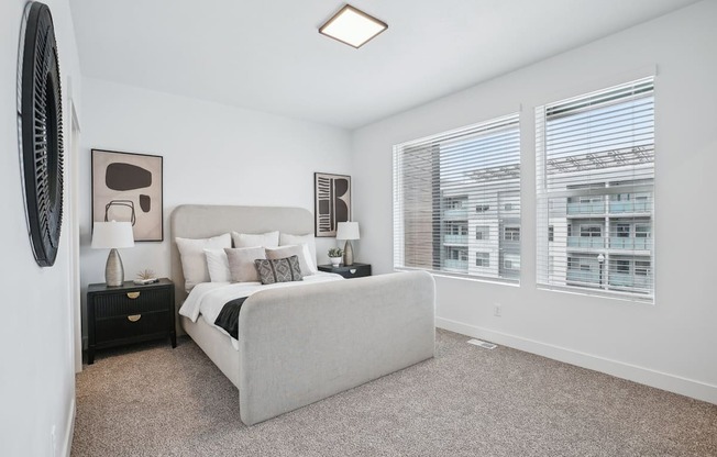 A bedroom with a large bed, a dresser, and a window with blinds.