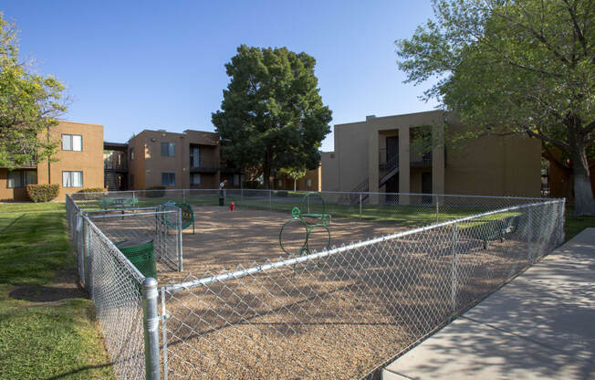 a fenced in playground in front of an apartment building