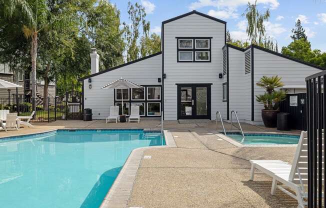 the pool is in front of a white house with a swimming pool