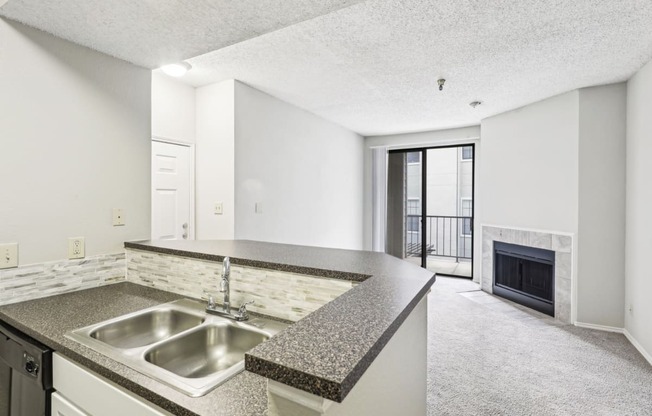 A1 floor plan kitchen with a sink and elevated counter overlooking the fireplace at Jefferson Creek Apartments in Irving, TX.