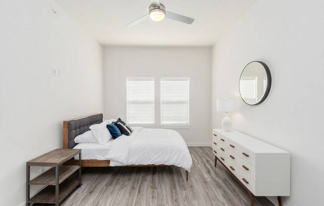 a bedroom with a bed and a dresser and a ceiling fan