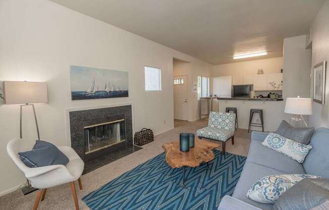 A living room with a grey couch, a fireplace, and a painting on the wall at Autumn Oaks Apartments, Roseville, CA, 95678
