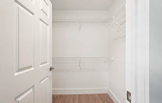 A white door is open to a room with a white wall and a brown carpet.