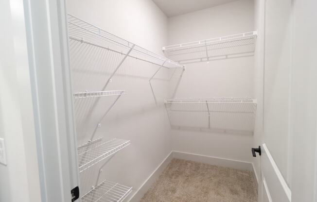 a walk in closet in a home with white walls and a white door