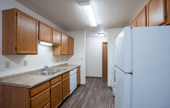 a kitchen with white appliances and wooden cabinets and a refrigerator. Fargo, ND  Prairie Park Apartments