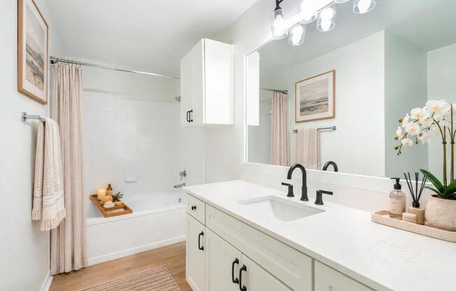 The light finish bathroom package features white shaker-style cabinetry, quartz countertops, matte black fixtures, a spacious vanity, and a soaking tub that create a bright, refreshed look.
