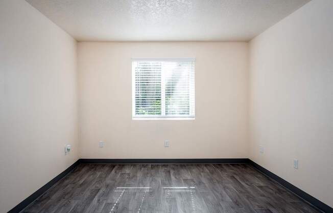 A room with a window and wooden floor.
