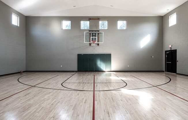 an empty gym with a basketball court and wood floors