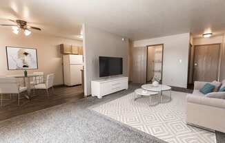 Grand Forks, ND Cherry Creek Apartments a living room with a white rug and white furniture with a dining room in the background