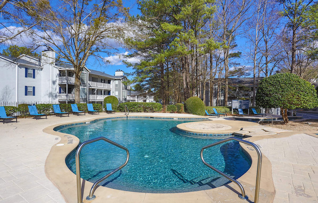 a swimming pool with blue chairs and a building in the background