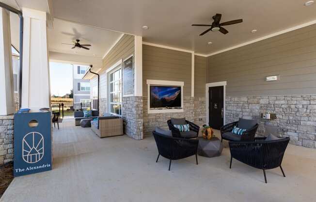 Outdoor resident lounge with seating, TV, and concrete flooring at The Alexandria in Madison, AL