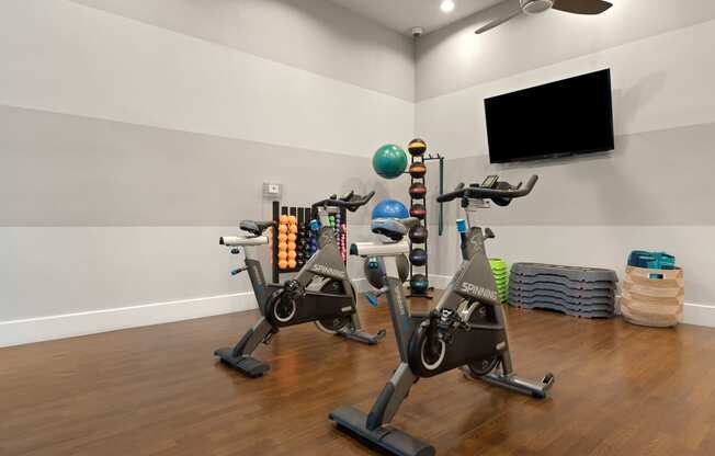 a room with two exercise bikes and a tv on the wall