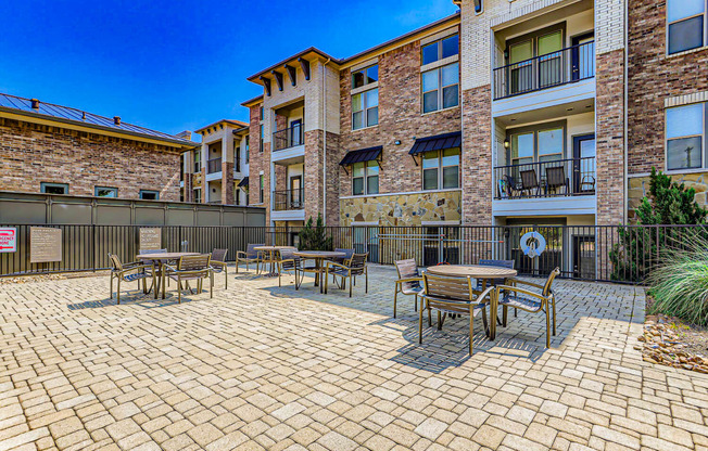 a patio with tables and chairs outside of an apartment building at Discovery at Craig Ranch, McKinney