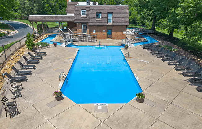 an aerial view of a swimming pool with a house in the background