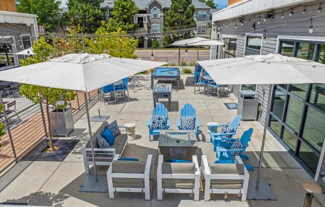 an outdoor patio with blue lounge chairs and white umbrellas