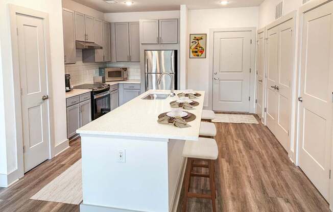 A kitchen with a white island and wooden floors.