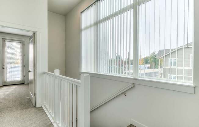 A white room with a carpeted floor and a staircase with white railings.