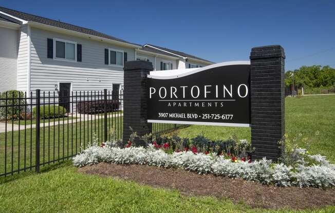 the sign in front of a property with a fence and flowers