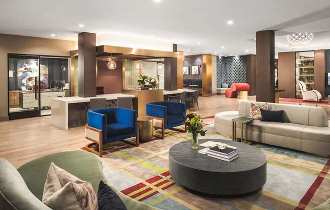 A modern living room with a variety of seating options and a colorful rug.