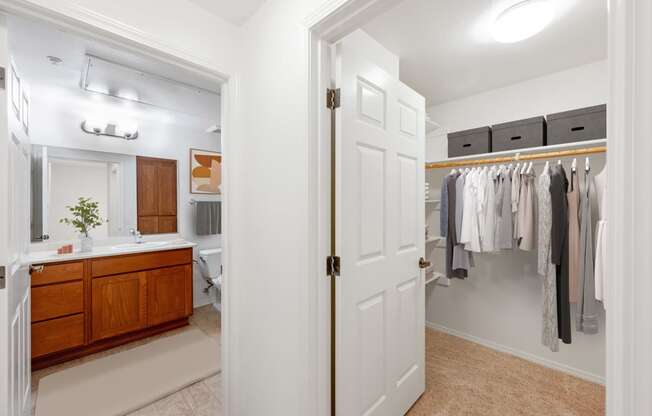 a bathroom with a white door and a closet full of clothes