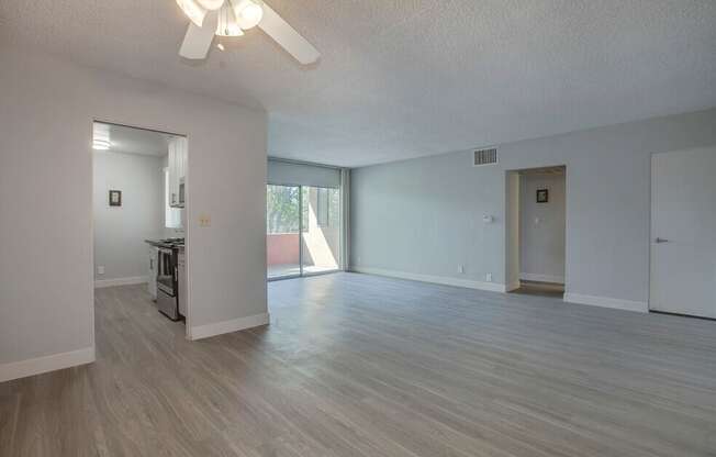 A spacious living room with a ceiling fan and lighting fixture.