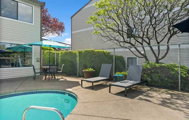 A pool with a chair and a table in the backyard.