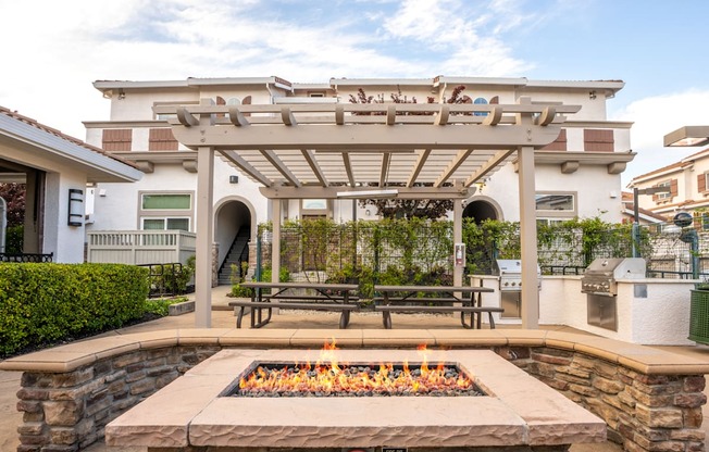 A patio with a fire pit and picnic tables.