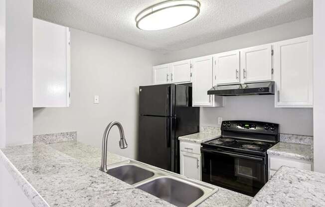 A kitchen with black appliances and white cabinets.
