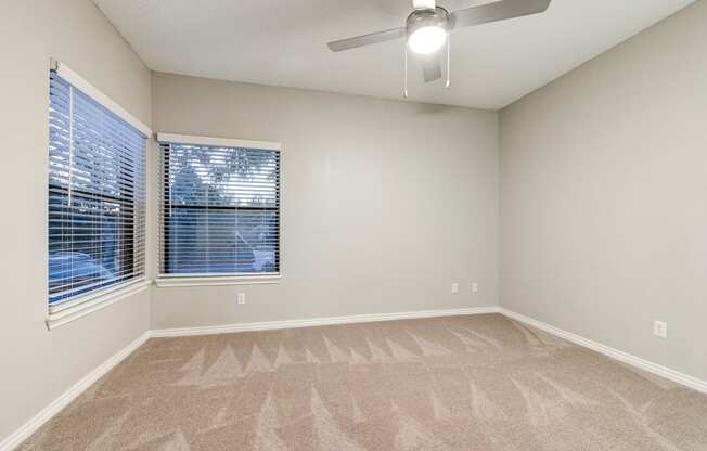 an empty living room with a large window and a ceiling fan at Ashford Belmar Apartments, Lakewood, 80226